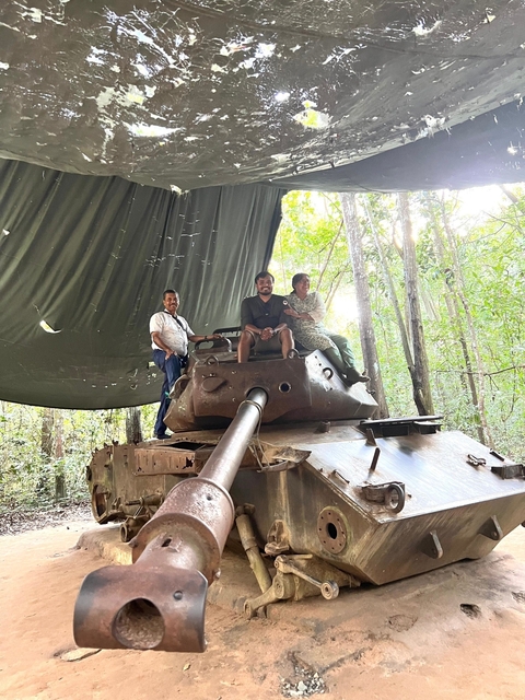       Visitors sitting on an old tank in a forest
  