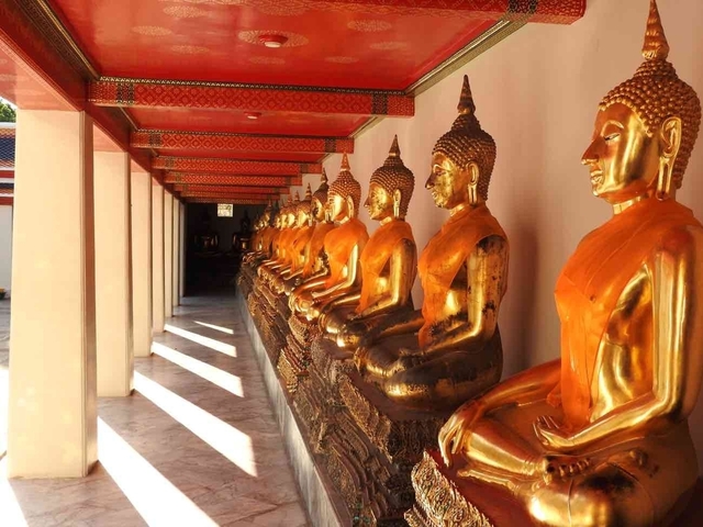 Row of golden Buddha statues in a temple corridor