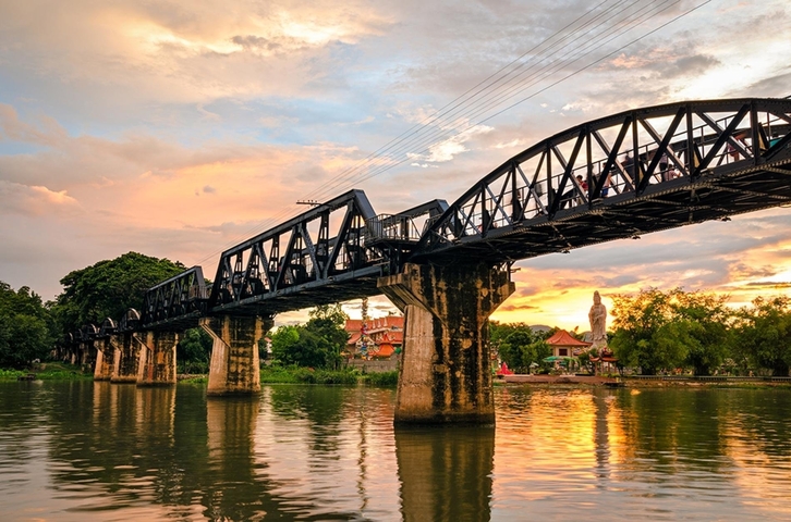 Historic iron bridge over a river at sunset
