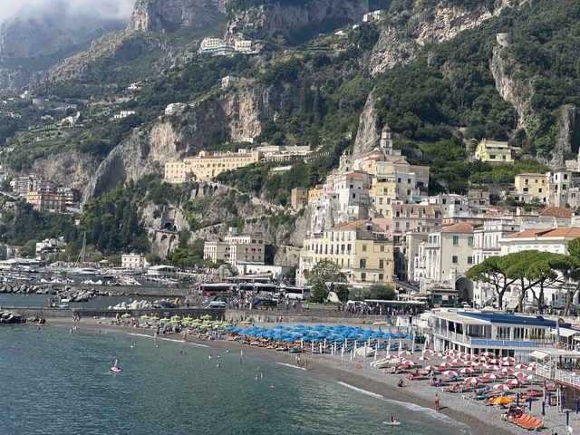 Coastal town with sandy beach and colorful beach umbrellas.