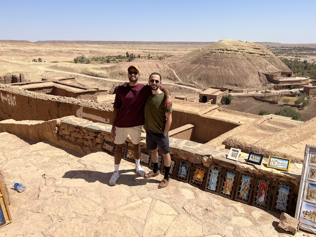 Two people posing with a scenic desert landscape.
