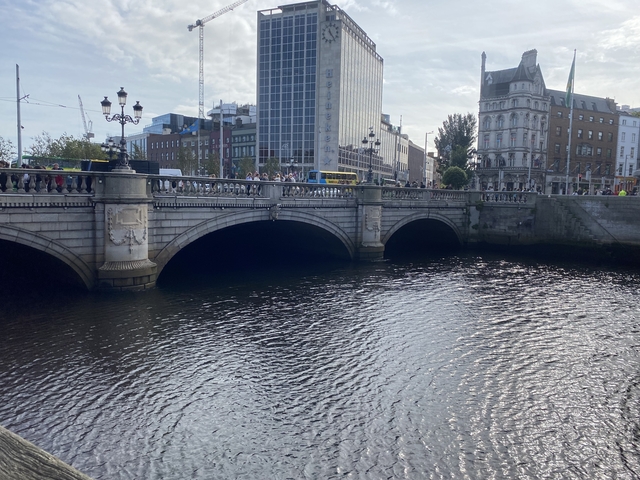 Ornate stone bridge over a river in a bustling urban environment.