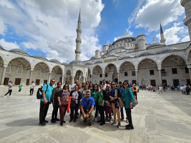       A group of tourists posing in front of a mosque courtyard.
  