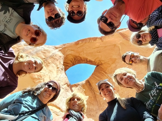 Group of people taking a photo under a natural rock arch.