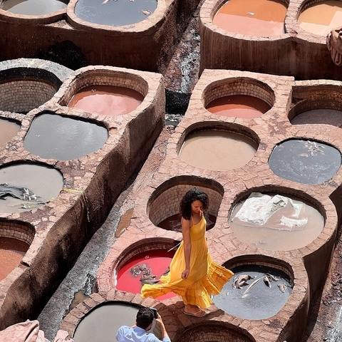 Person walking among large vats of dye in a tannery.