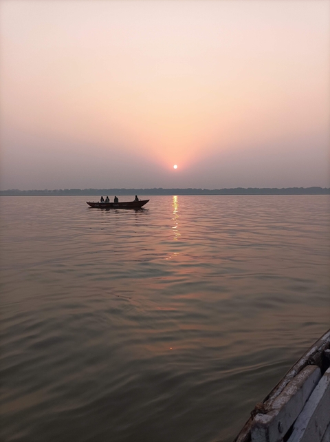 A small boat with people on a river during sunset.
