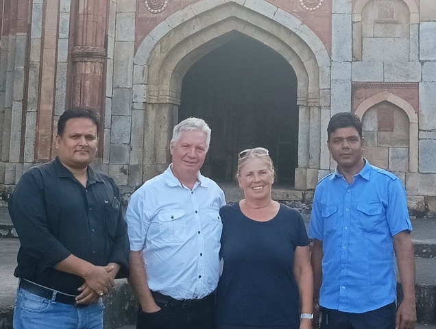 Group of four people posing in front of a historical building.