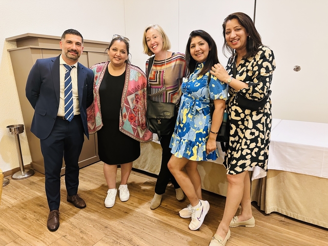 Five people in a room posing for a group photo.