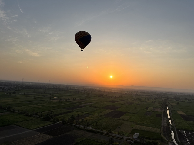       Hot air balloon over fields during a beautiful sunset.
  