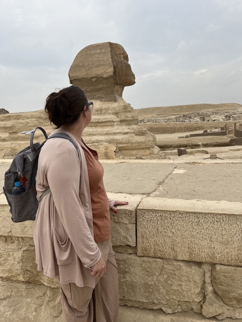       Woman looking at a statue in a desert-like environment.
  