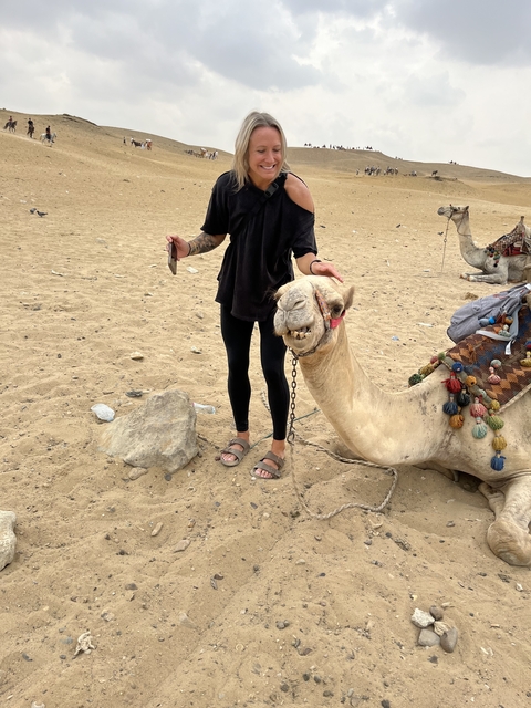       Person standing with a camel in a desert setting.
  