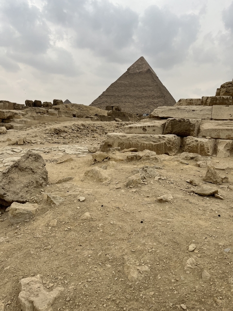       Rough terrain with historical stone structures in the background.
  