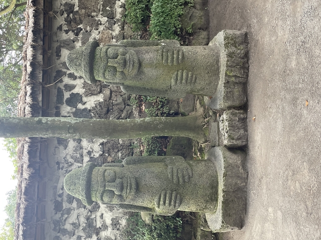 Statues of two large stone figures under trees.