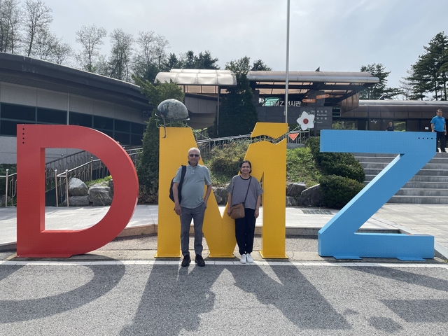       Tourists at the DMZ exhibit with large DMZ signs.
  