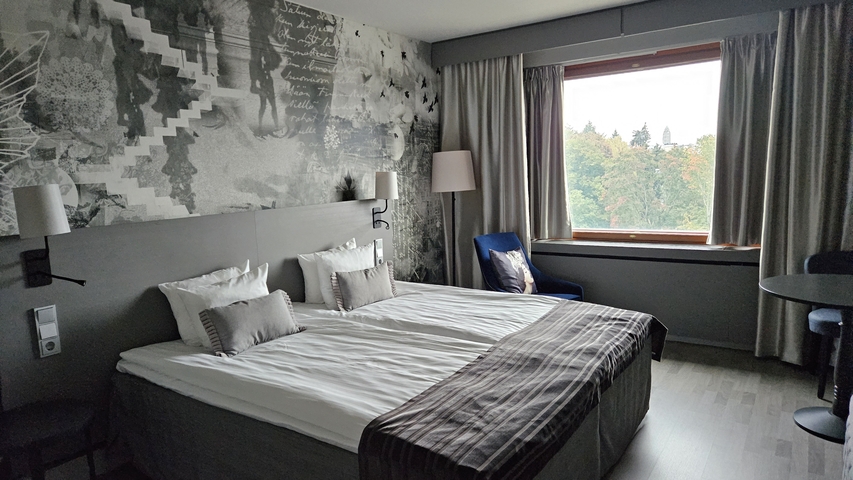 A hotel room interior with a view of trees outside.