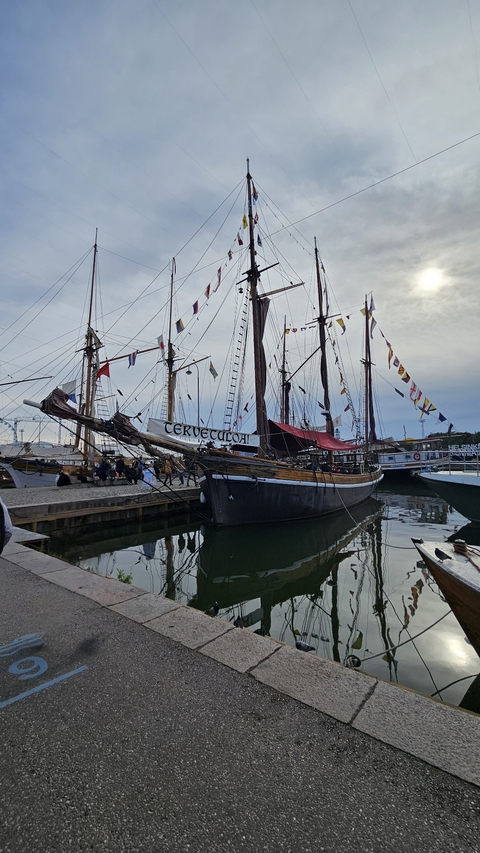 A docked boat with colorful flags on a cloudy day.