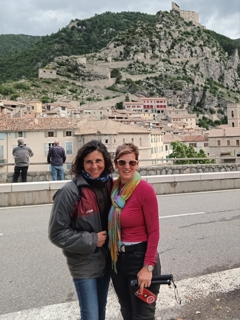Two people posing with a historic town in the background.
