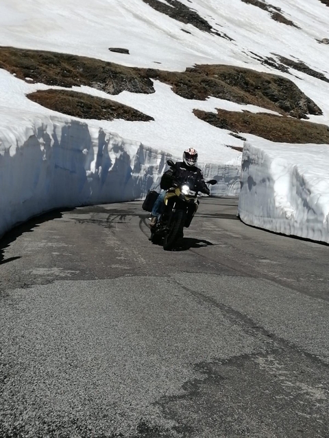       A motorcyclist riding on a road flanked by snow.
  