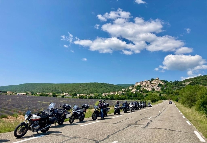       A line of motorcycles on a country road with hills in the background.
  