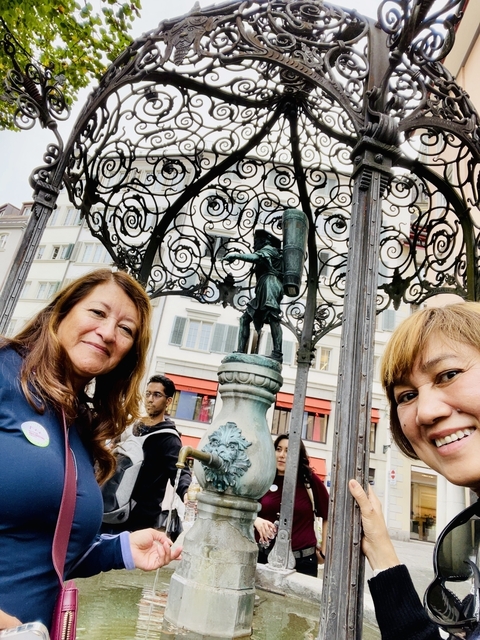 Two people standing near a historic fountain.