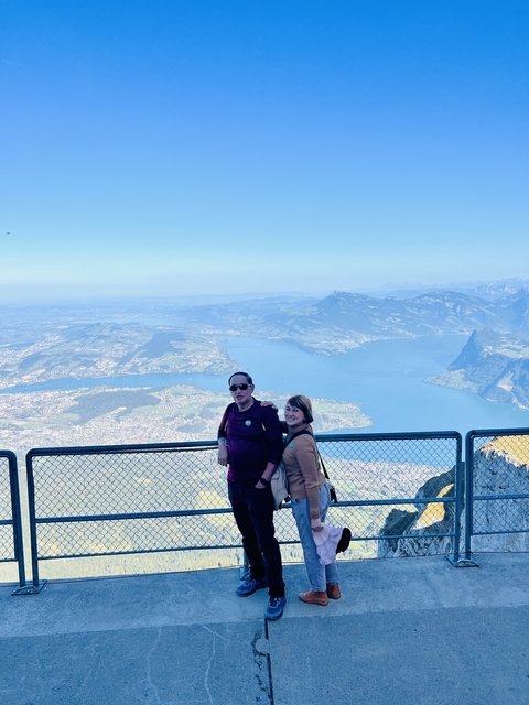Couple at a viewpoint overlooking a lake and mountains.
