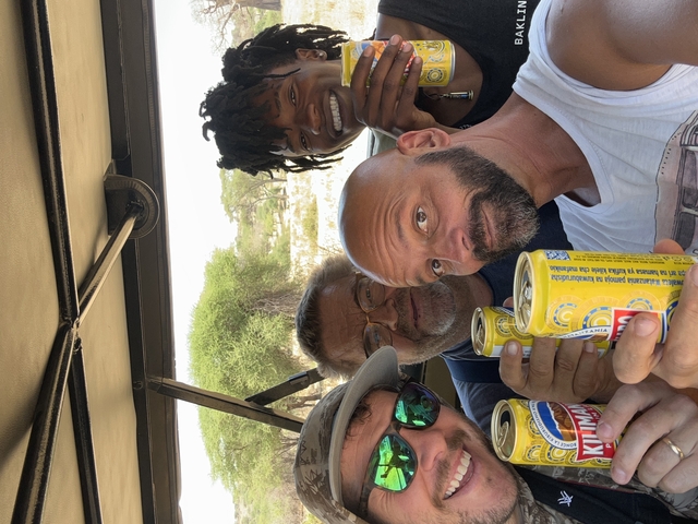 Group of people holding beverages inside a safari vehicle.