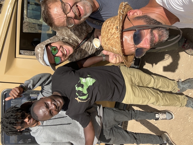 Group of people posing for a photo with a safari vehicle.