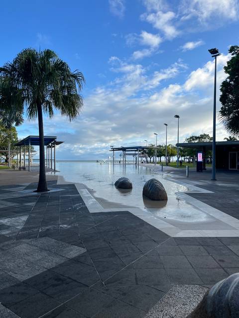      A paved walkway by the ocean with some artistic structures.
  