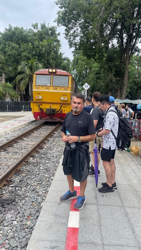 Man standing near railway tracks with a train approaching.