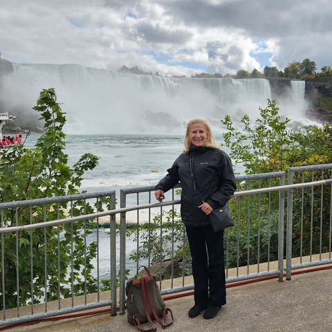 Woman posing by a railing with Niagara Falls in the background.