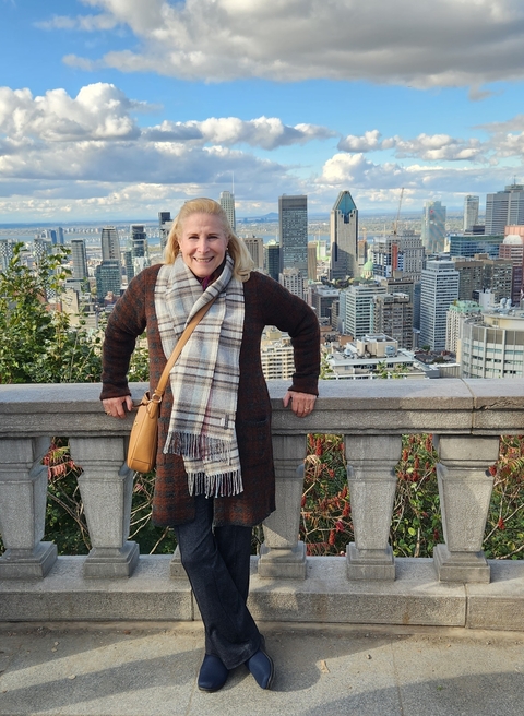 Woman smiling on a Montreal overlook with cityscape.
