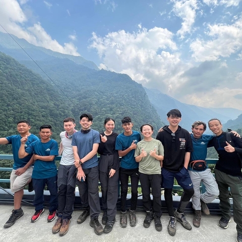       Group smiling and posing with mountain backdrop.
  