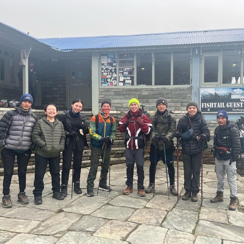       Group of people standing in front of a guesthouse.
  
