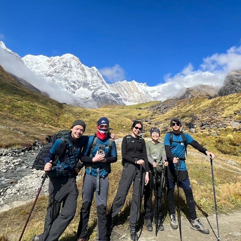       Hikers posing with snow-capped mountains in the background.
  
