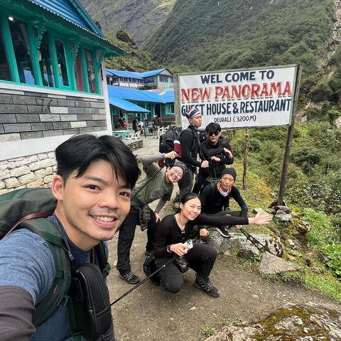       Group of hikers posing with a guest house sign.
  