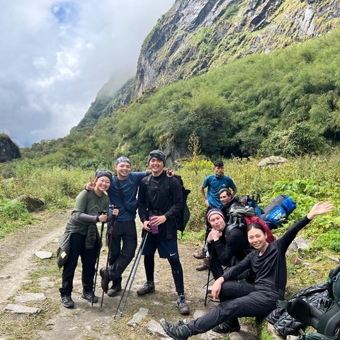       Hiking group posing together on a trail in a mountainous area.
  