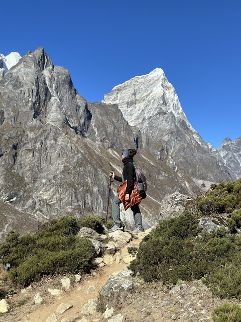       Person looking at a towering mountain in a rocky landscape.
  