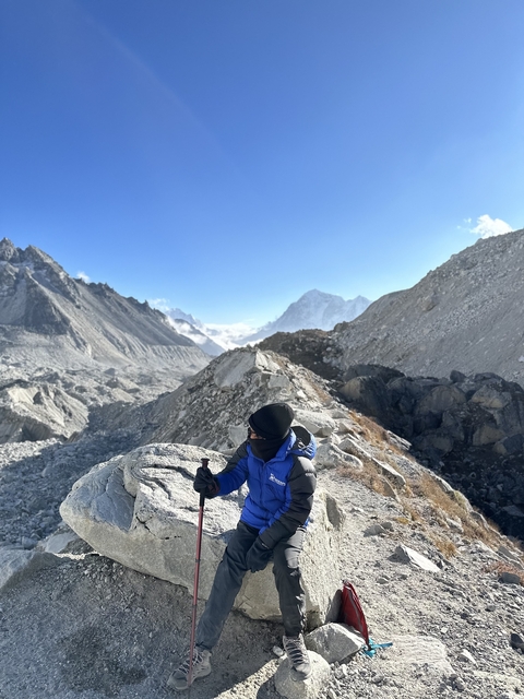       Hiker giving a thumbs up in a rocky Himalayan landscape.
  