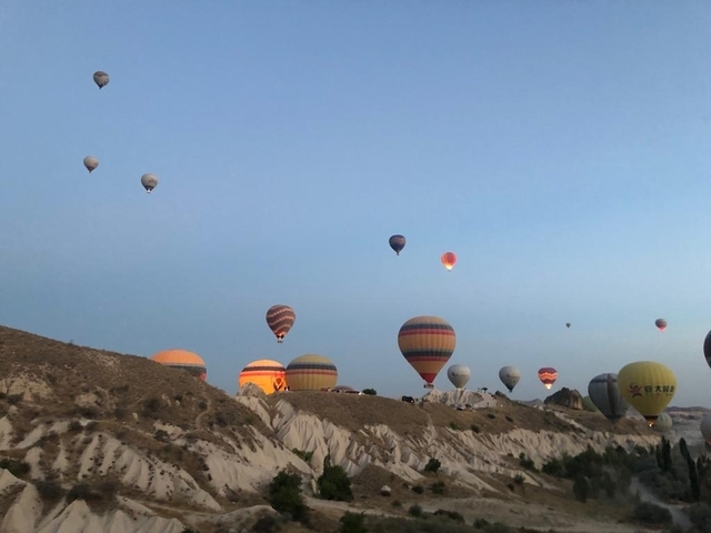 Hot air balloons floating above a rocky terrain.