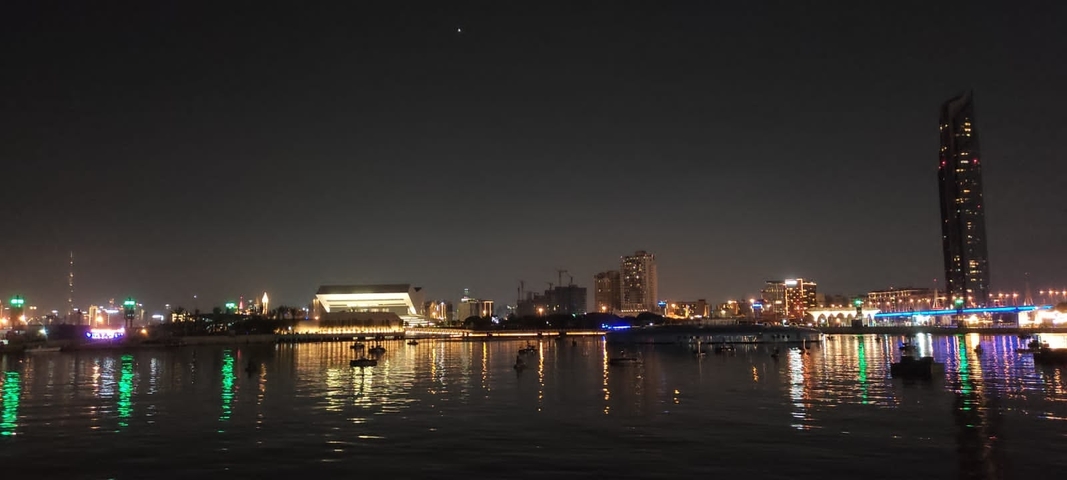Cityscape with building lights reflecting on water.