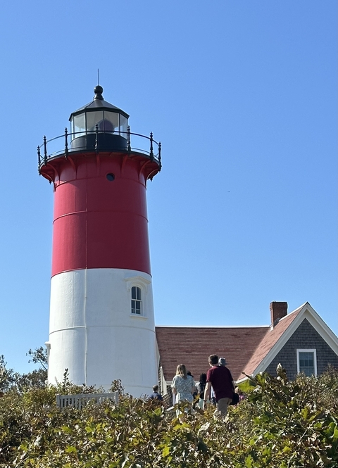       Lighthouse with red and white stripes against a clear sky.
  
