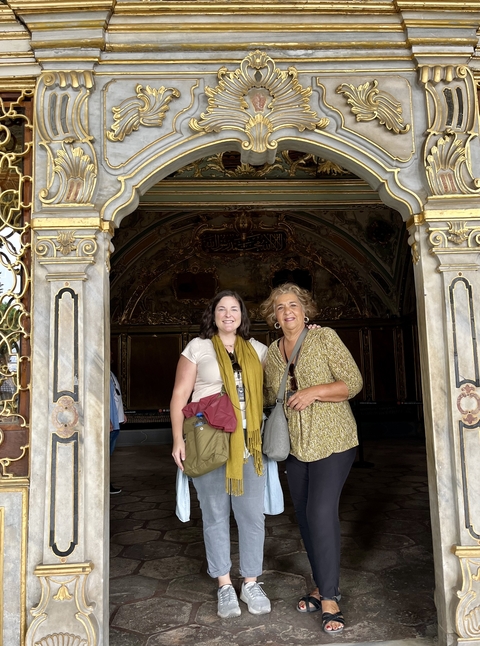       Two women posing at an ornately decorated entrance
  