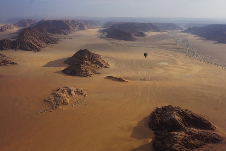Sweeping aerial view of Wadi Rum desert with hot air balloon