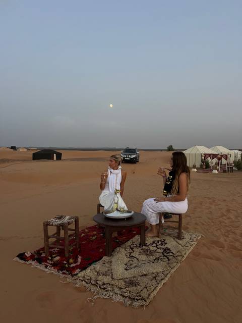       Two women having tea in the desert.
  