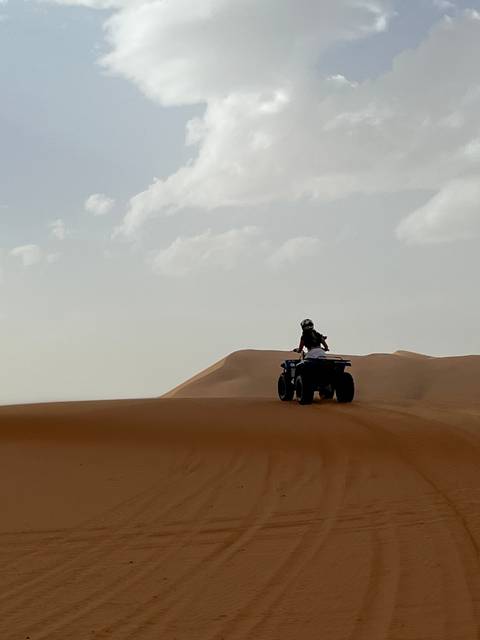 Person on a quad bike in desert dunes.