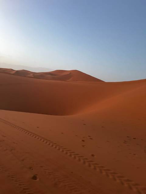 Desert landscape with dunes and blue sky.