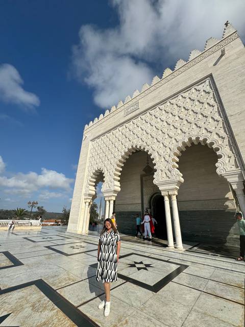 A woman standing near an ornately decorated architectural structure.