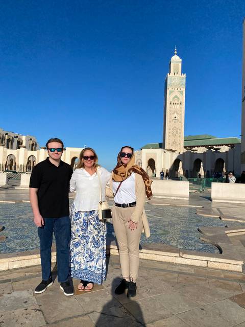 Three people posing in front of a mosque.