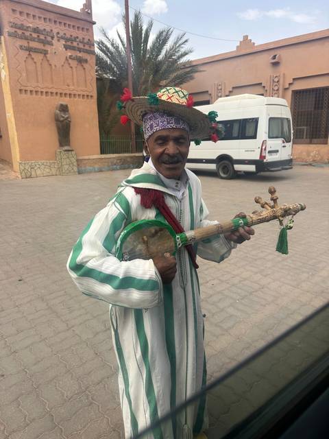       Street performer wearing traditional attire and holding a musical instrument.
  