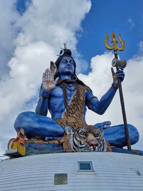Large statue of a deity against a blue sky.